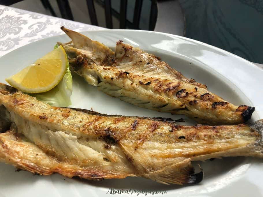 white plate with split grilled whole fish and piece of lemon at Fish Grill Hidri, Tirana