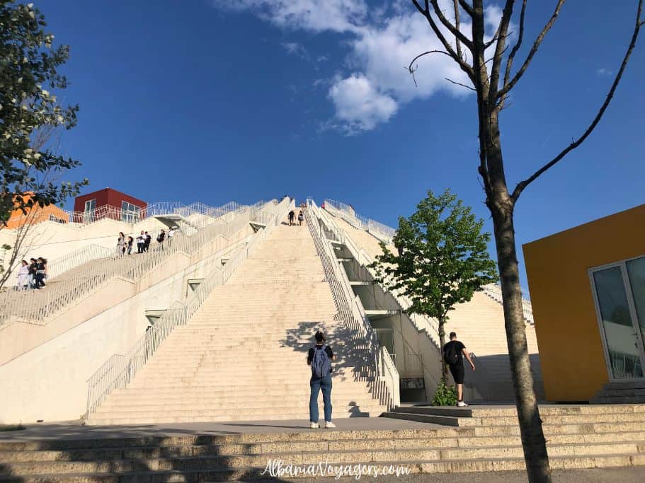 The Pyramid in Tirana with people walking up the stairs and blue sky