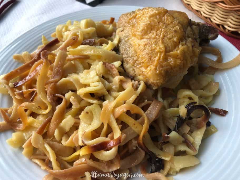white plate with wide, long noodls and piece of chicken, one of the most traditional Albanian foods