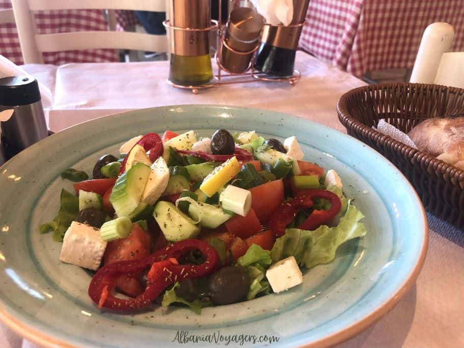 salad with feta, cucumbers, tomatoes, peppers, olives and lettuce on a blue bowl, one of the best things to eat in Tirana
