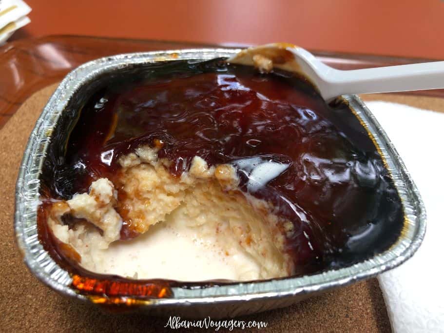 Albanian trilece in metal serving cup with bite taken out and plastic spoon, this is what you should eat for dessert in Tirana