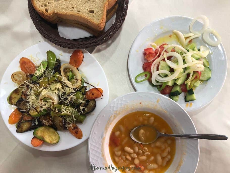 bowl of soup, plate of salad, plate of grilled vegetables and basket of bread on white table cloth at Sibora in Tirana