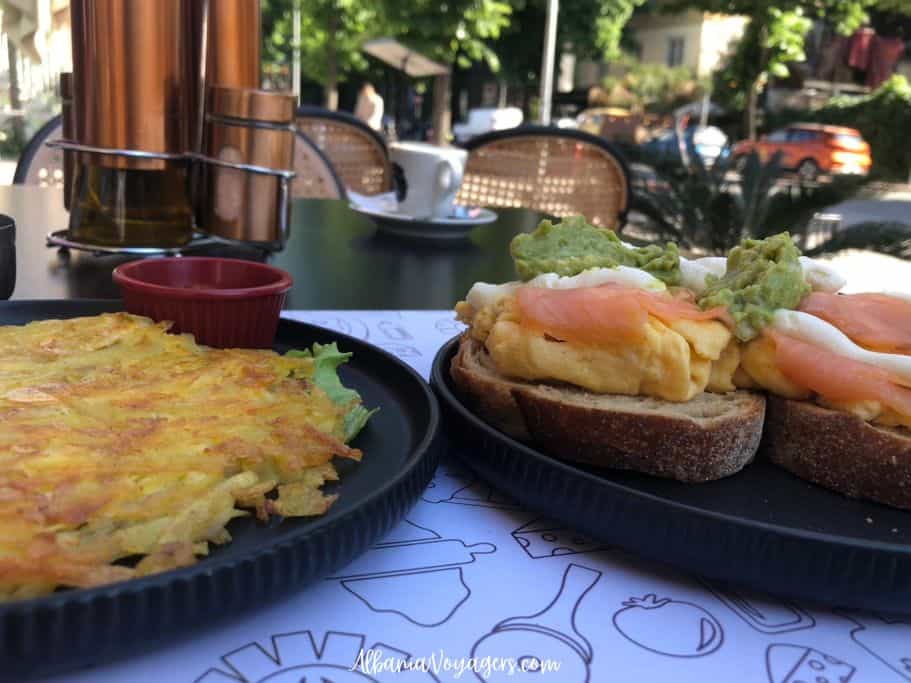 two dark plates of hash browns and eggs on toast on outdoor table at Tony's in Tirana