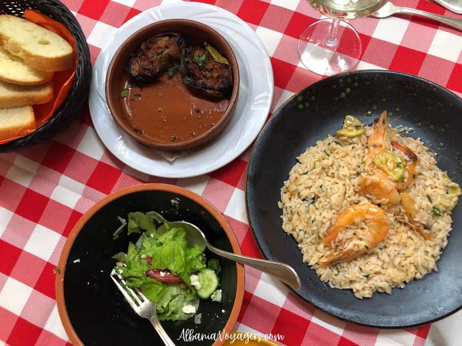 plate of shrimp risotto, bowl of salad, and suffed zuchini on red and white checked table cloth at Restorant Metropol
