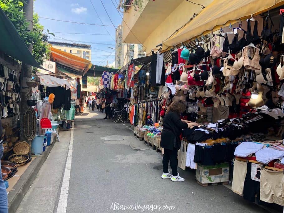 Rruga Zela street market with street side stalls on both sides and a bunch of bras hanging up in Tirana