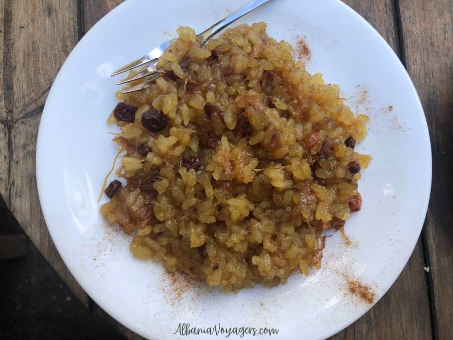 white plate with light brown rice dessert and fork in Kruja