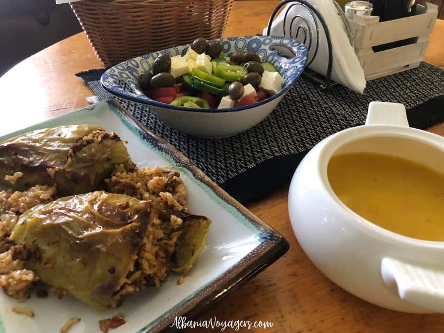 square plate of stuffed pepper, small white tureen with carrot ginger soup and blue bowl with Greek salad on blue and white place mat at Te Nona N'Durres