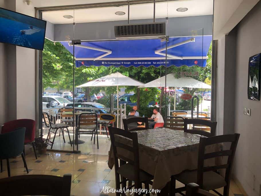 Interior of Bar Rosticeri Gazi with square tables and blue awning outside