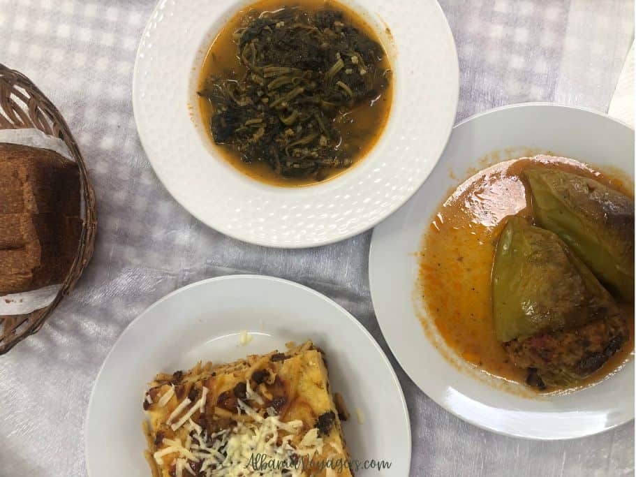White dishes of spinach, stuffed peppers and big piece of pastitsio and bread basket at Liriada in Durres