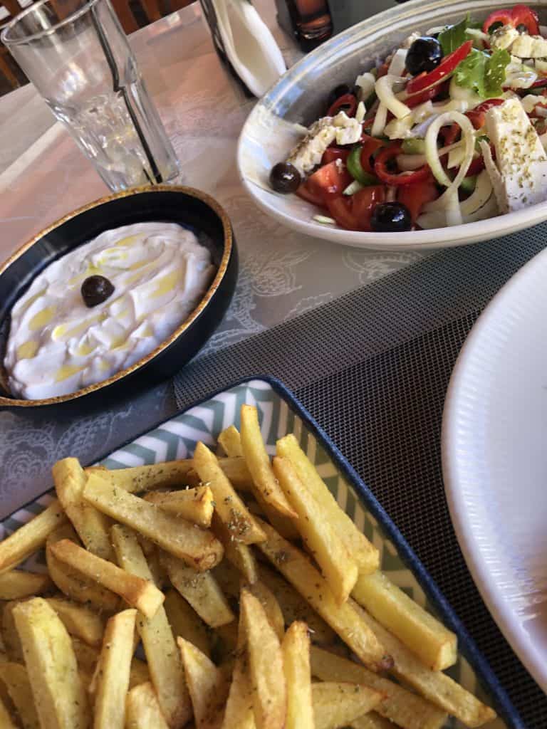 plates of Greek salad, home fries and tzatziki at Taverna Ulson
