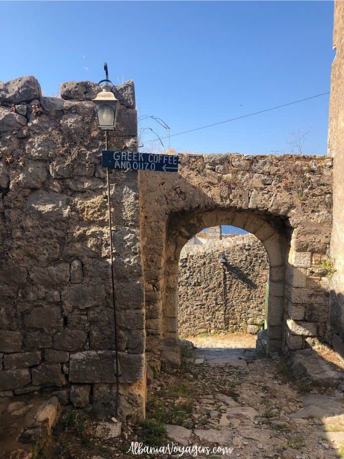 old stone wall with blue sign for ouzo and coffee in Himare