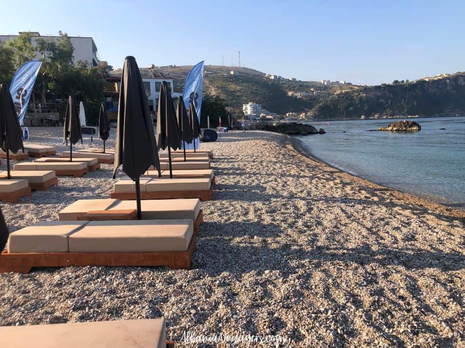 looking long ways down Prinos Beach in Himare with loungers and umbrellas