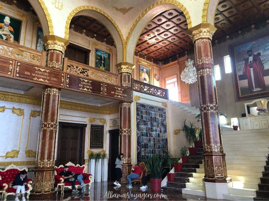inside the Bektashi Tekke in Saranada with high vaulted ceilings, large paintings and people sitting around on red couches