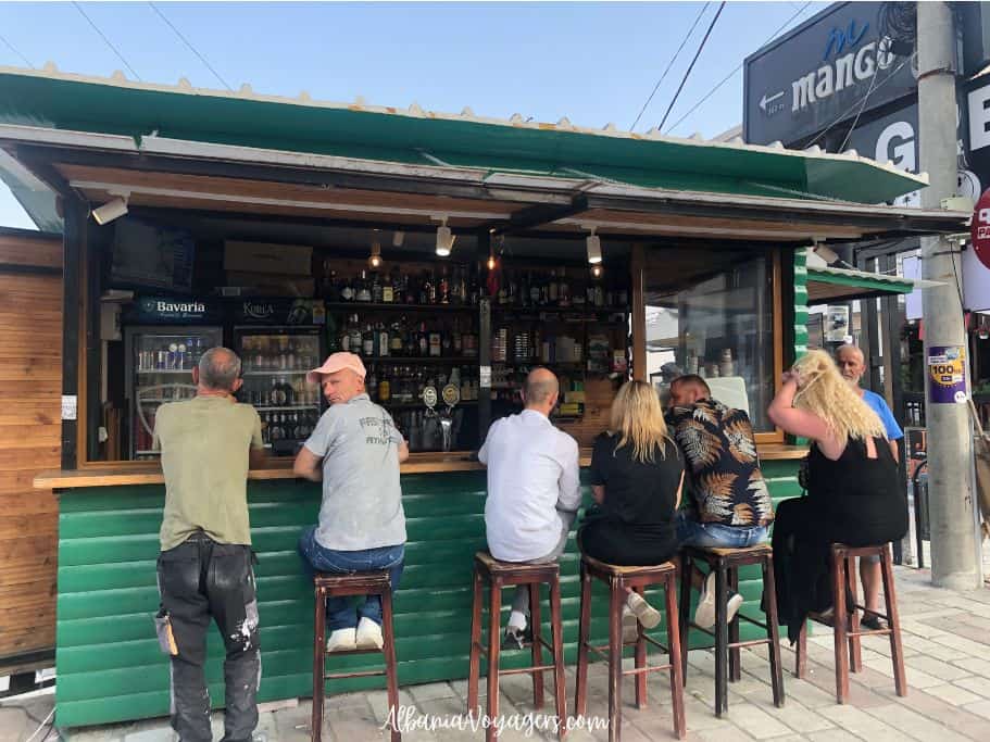 roadside bar with people sitting on stools in Ksamil