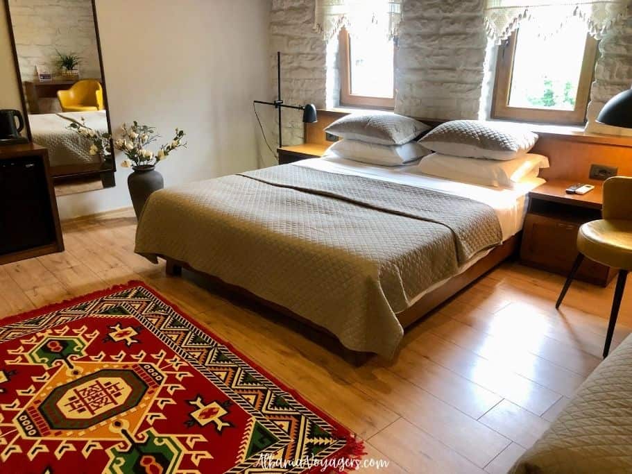 Room at Stone Sky Hotel in Gjirokaster with double bed, wood floors and traditional rug