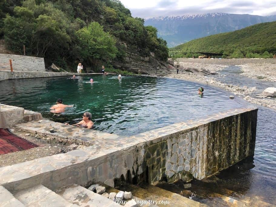 large thermal pool with several people bathing and mountain views