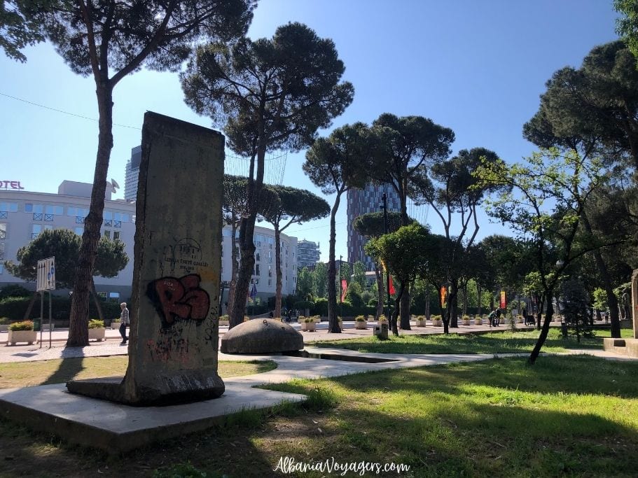 Slab from the Berlin Wall and concrete bunker in Checkpoint Park, with grass, trees and blue sky