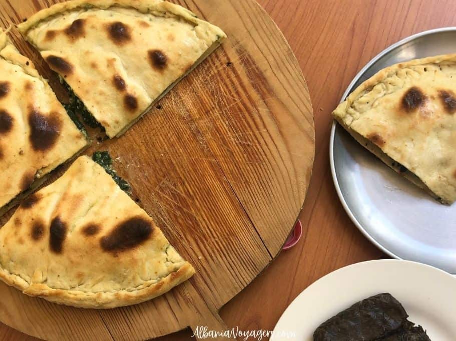 3 wedges of spinach lakror on wooden serving board with one wedge on metal plate