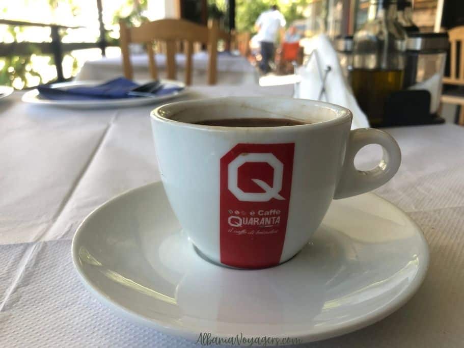 close up of white coffee cup on saucer filled with Greek coffee on white table cloth