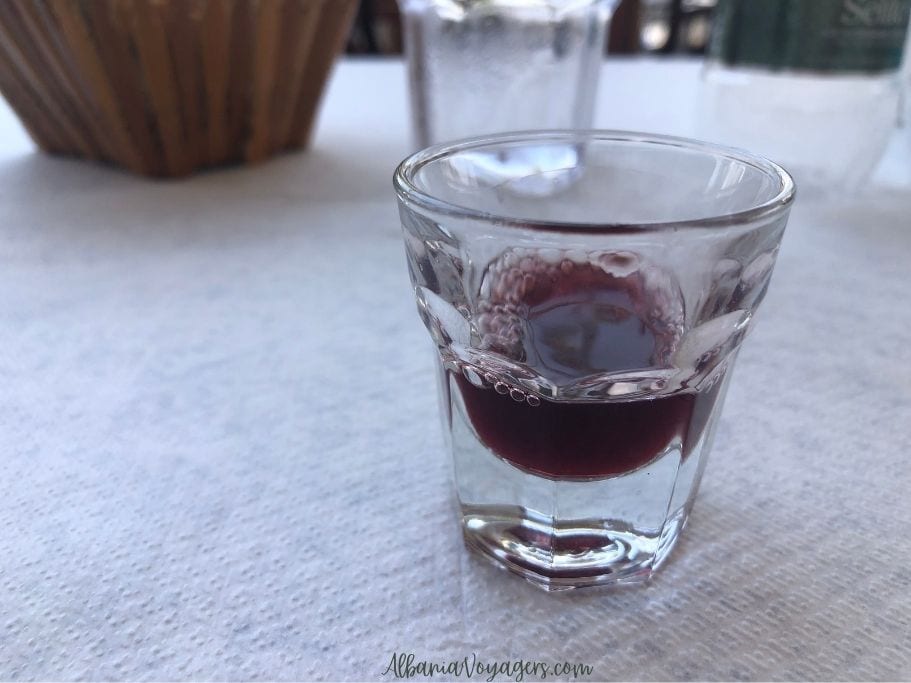 close up of shot glass with cinnamon raki on white table cloth