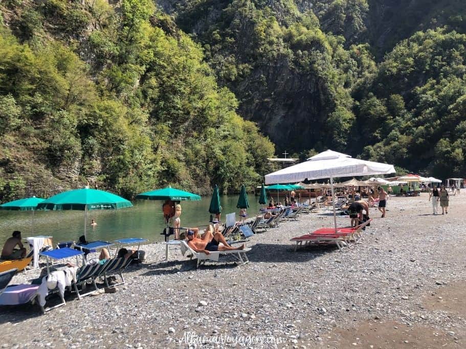 lots of assorted sunbed and umbrellas with people sunbathing on the Shala River