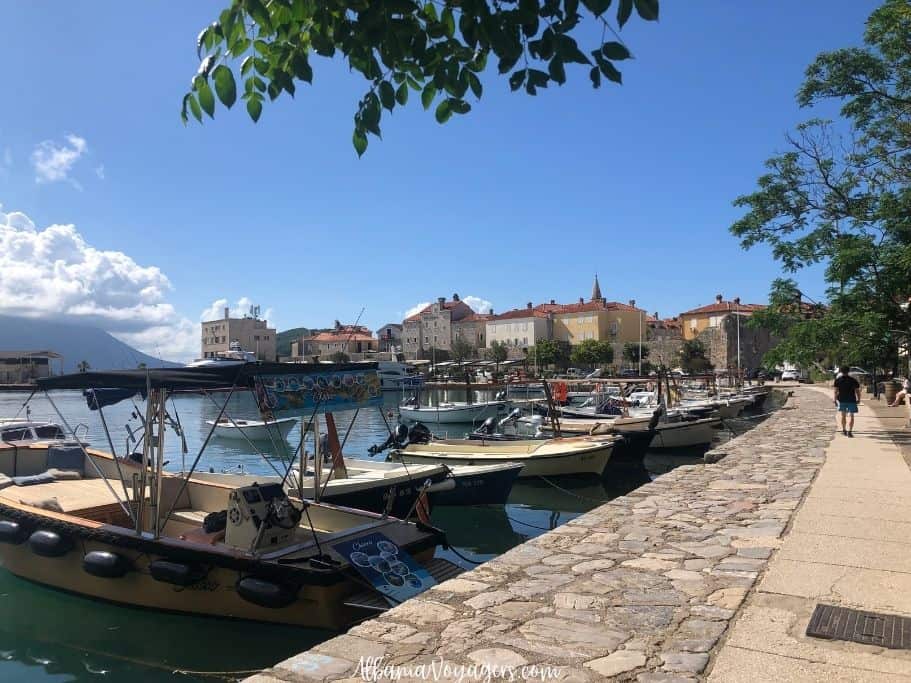 Budva waterfront with boats and trees looking toward walled old city