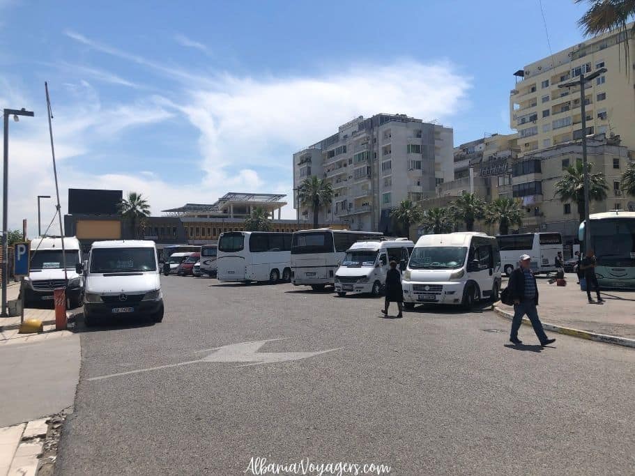 view of Durres bus station with white buses and fugons parked, one of the best ways to get to Shkoder