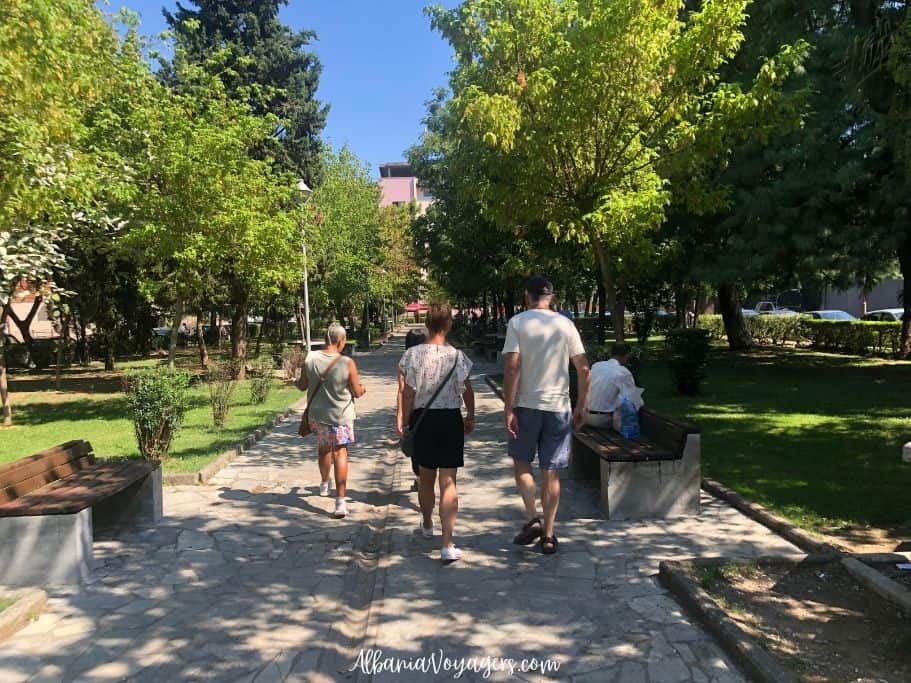three people walking through a park from behind