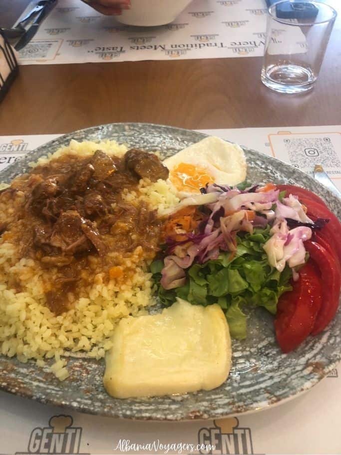 Large round plate with rice,goulash, fried egg, cheese and salad at Genti Restaurant in Shkoder