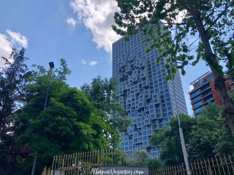 full view of Downtown One building in Tirana with trees and blue sky, something you will see on your city break