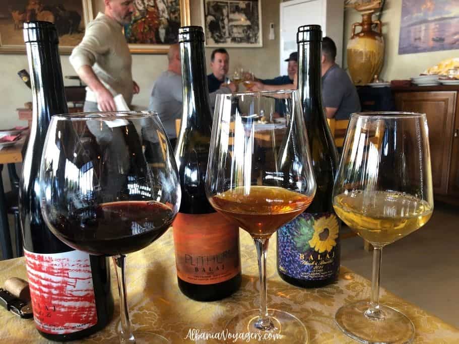 3 filled wine glasses in front of wine bottles at Kantina Balaj near Vlore