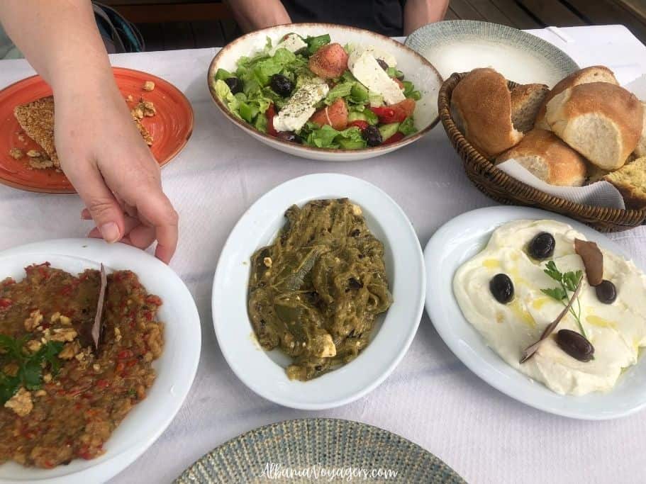 multiple plats of dips, salad and basket of bread at Mesopotam Agroturizem near Saranda