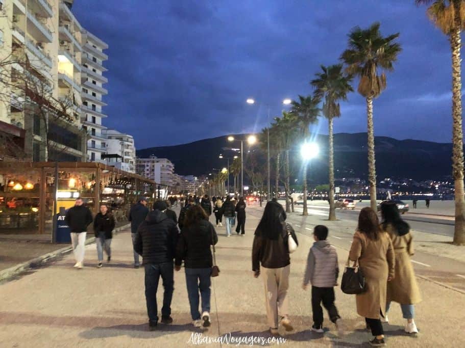 people walking in coats at night on the Lungomare Promenade in Vlore