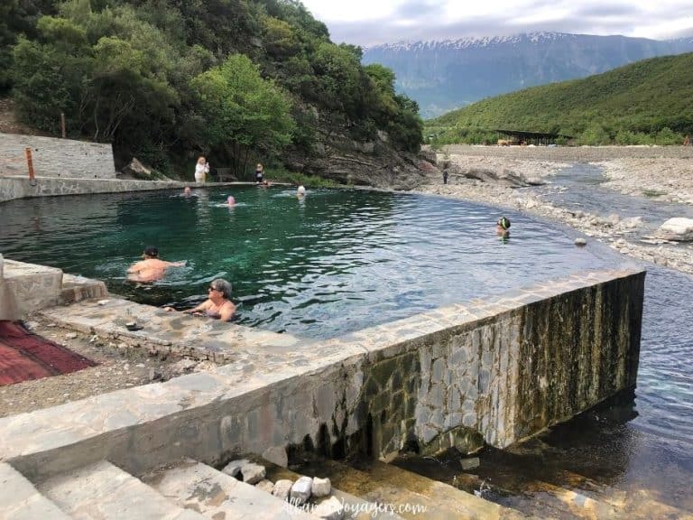 people in large thermal pool with snow capped moutain in background at Benja Hot Springs