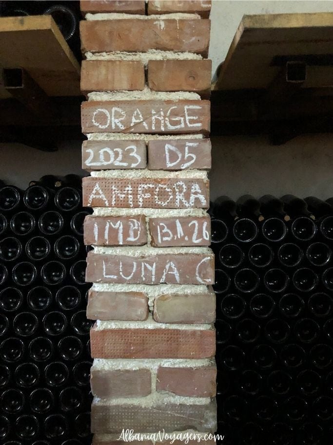 wine bottles stacked on both sides of brick column indicating the year and vintage in white chalk at Kantina Balaj