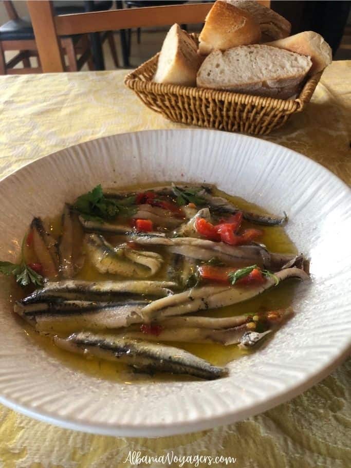 white plate of anchovy crudo and basket of bread at Kantina Balaj