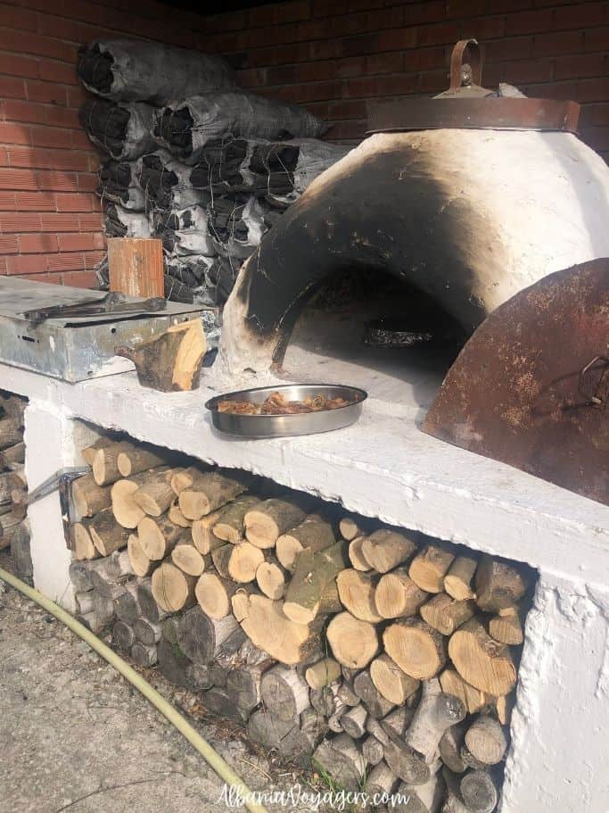 outdoor wood oven with stacked firewood underneath at Tamo's Farm