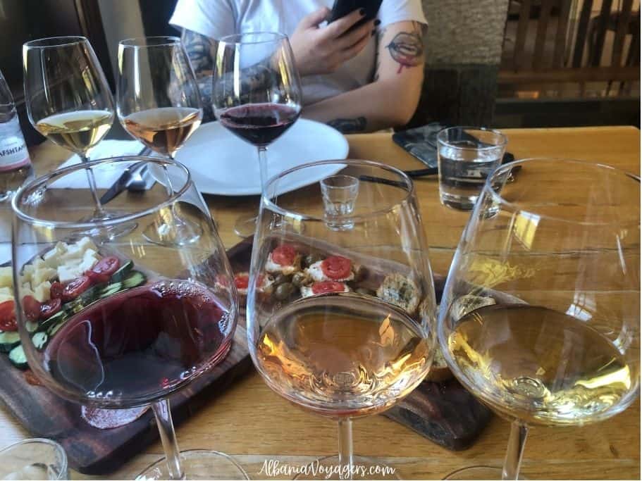 3 glasses of wine and appetizers on wooden table at wine tasting near Berat at Pupa Winery