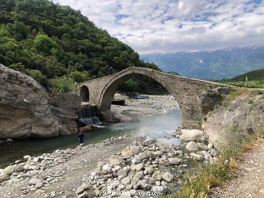 view of Kadiut Bridge and man fishing at Benja Therma Pools in Albania