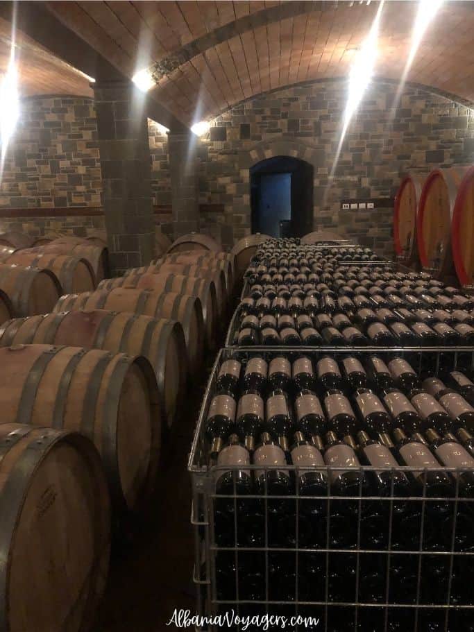 Stone and wooden ceiling cellar with wine barrels and wine racks at Pupa Winery