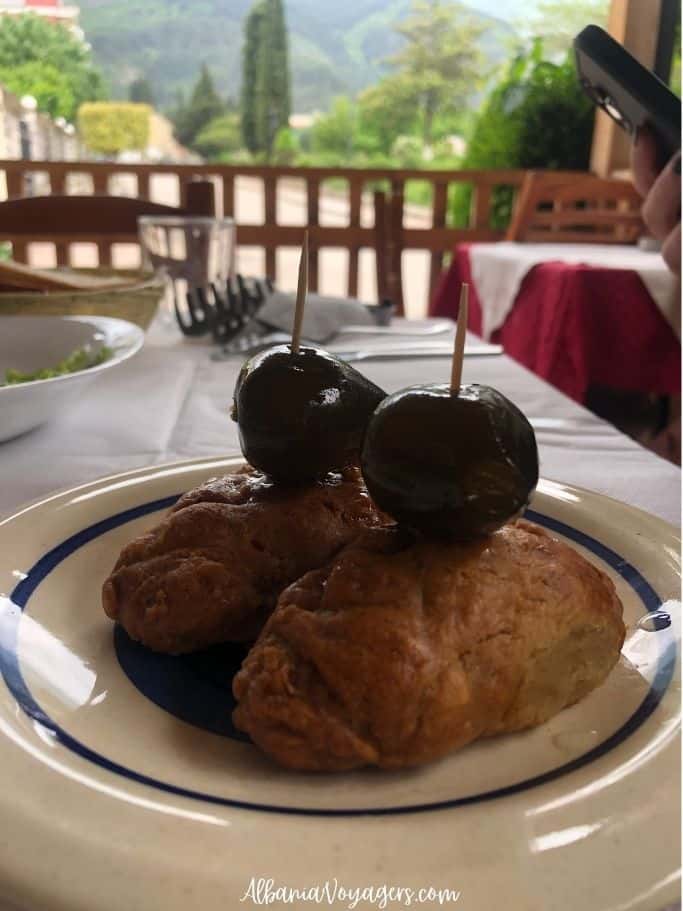 dessert of melomakaron cookies with candied fig on top on outside table at Te Culi in Permet, slow food