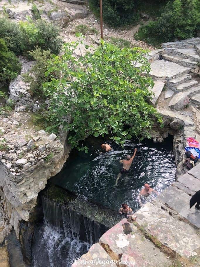 small hot spring with people bathing in it at the thermal baths near Permet