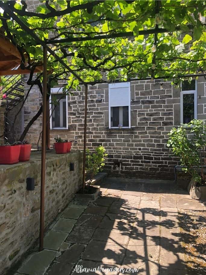 outdoor stone terrace covered in grape vines at Mosaic House in Permet